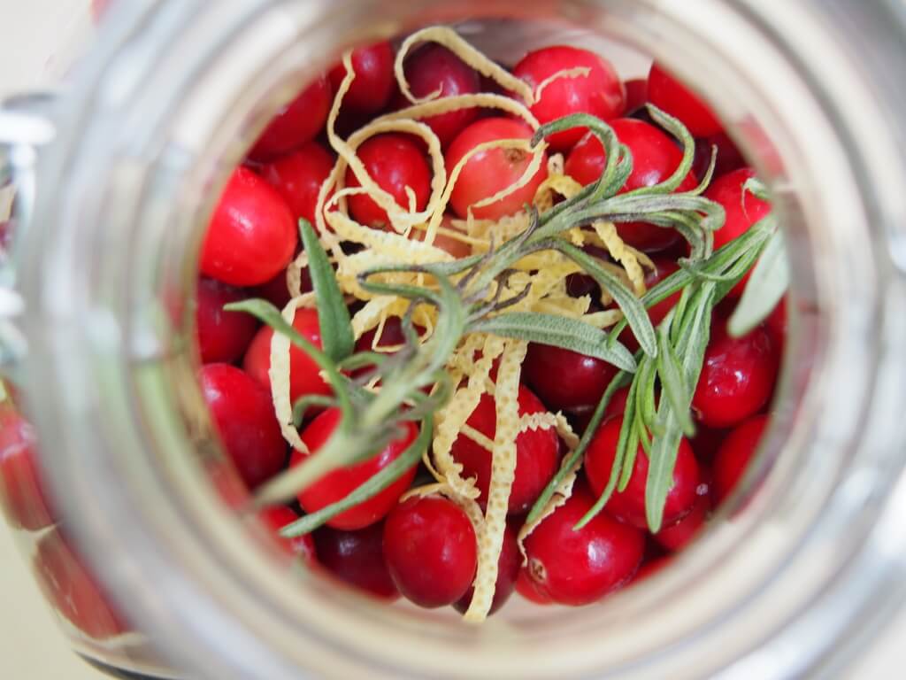 rosemary and lemon zest on top of cranberries in jar