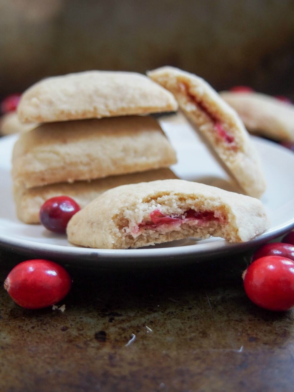 bitten-into cookie in front of stack showing cranberry filling in middle