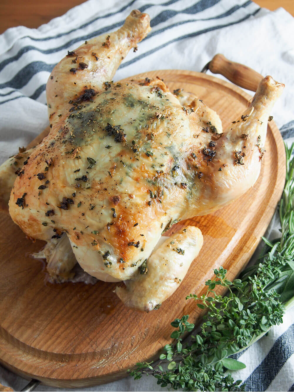 This garlic herb roasted chicken ups your roasting game by adding herbs, garlic & butter under the skin for extra flavor. Comforting, easy and delicious. whole garlic herb roasted chicken on carving board