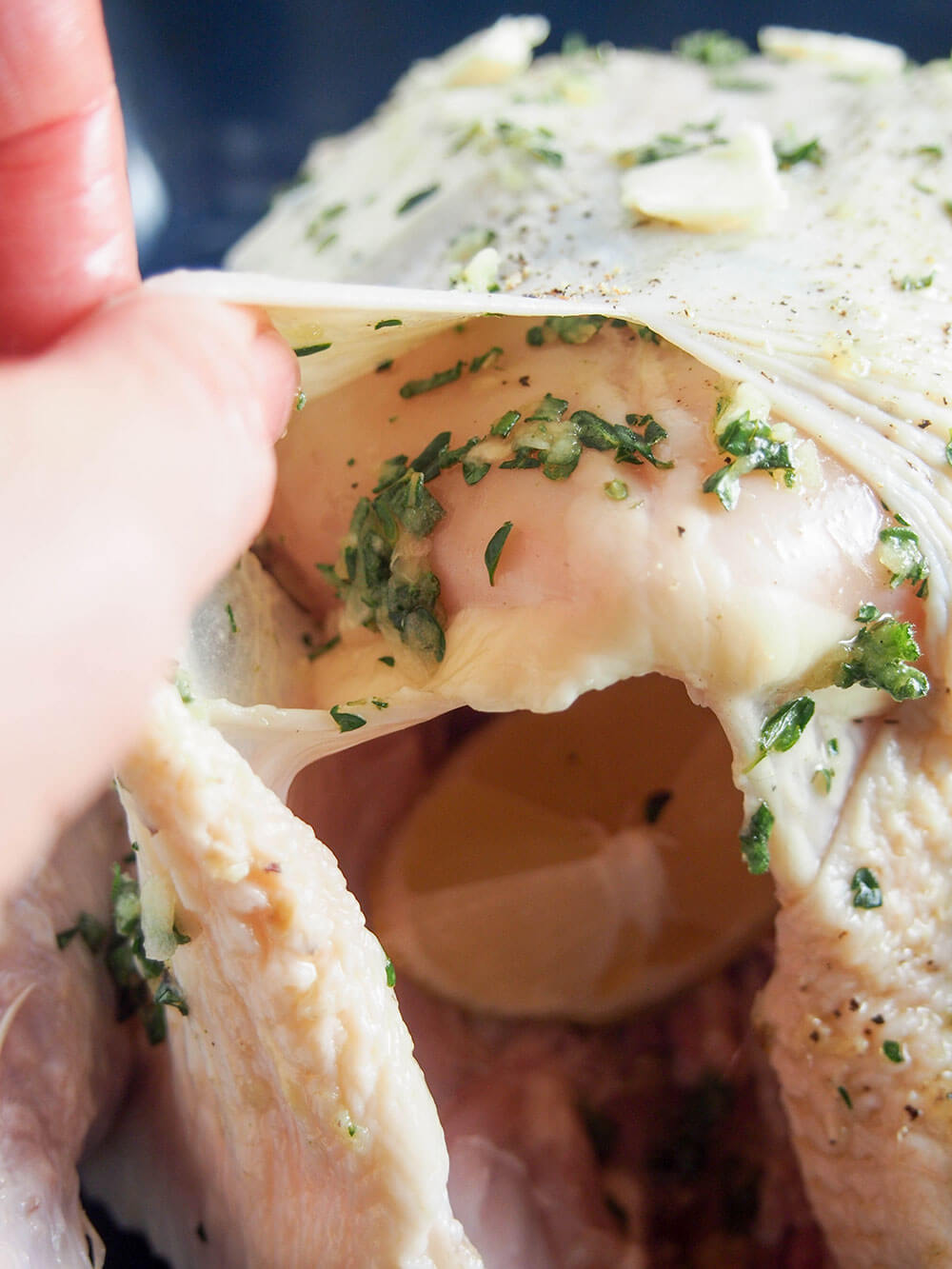 putting garlic herb mixture under skin for roast chicken stuffing garlic herb mixture under skin
