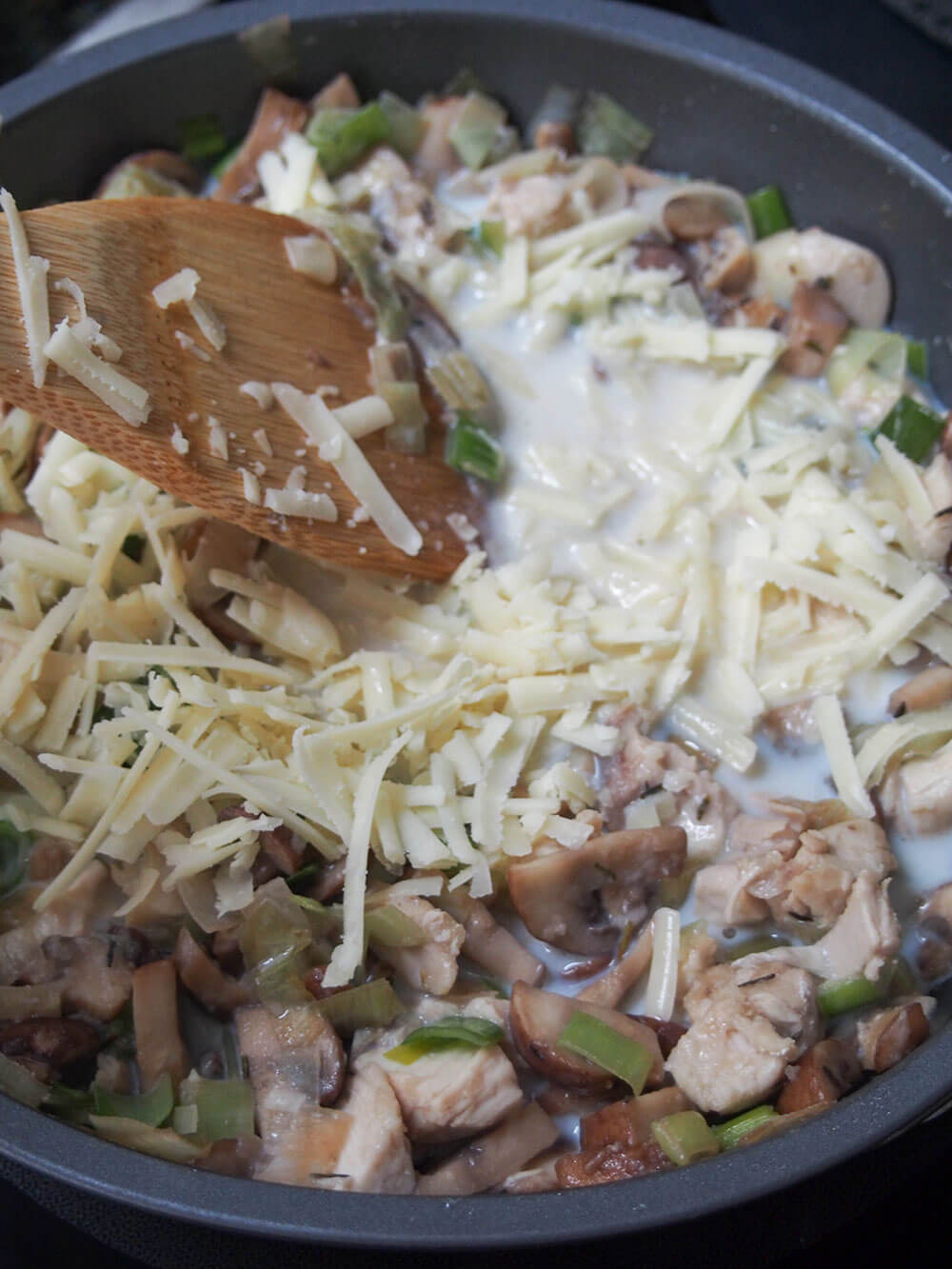 adding cheese to filling for chicken crepes with leek and mushrooms adding cheese and milk into filling mixture