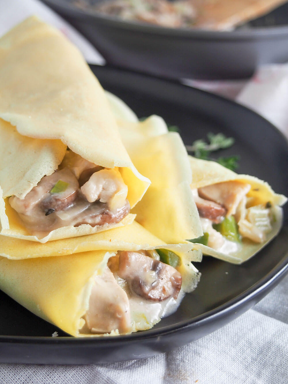 These turkey or chicken crepes with leek and mushrooms are a great way to use leftover meat in a tasty comforting dish. Chicken crepes with leek and mushroom close up showing filling at end of crepes
