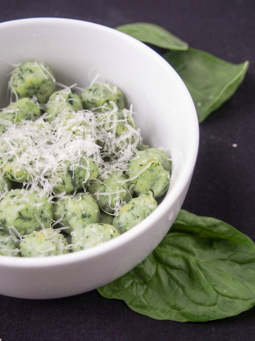 partial view of potato spinach gnocchi topped with parmesan