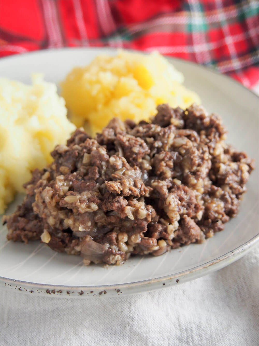 close up of simplified haggis with potatoes and swede behind