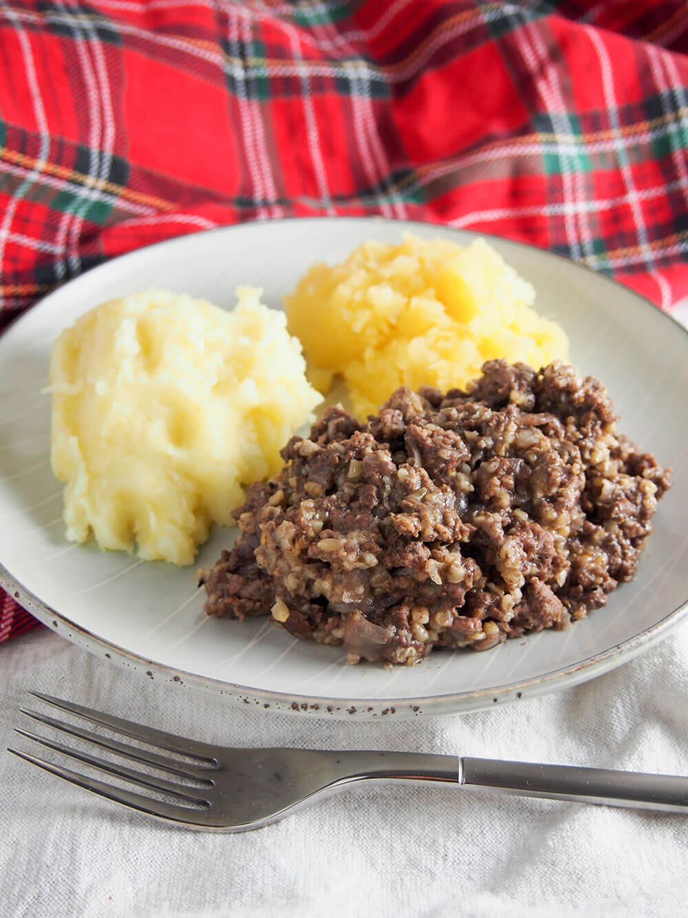 plate of haggis, neeps and tatties with fork in front of plate