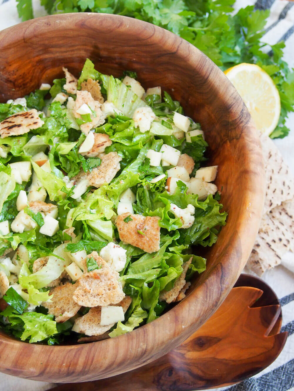 Winter fattoush salad in bowl with serving spoon & fork under bowl