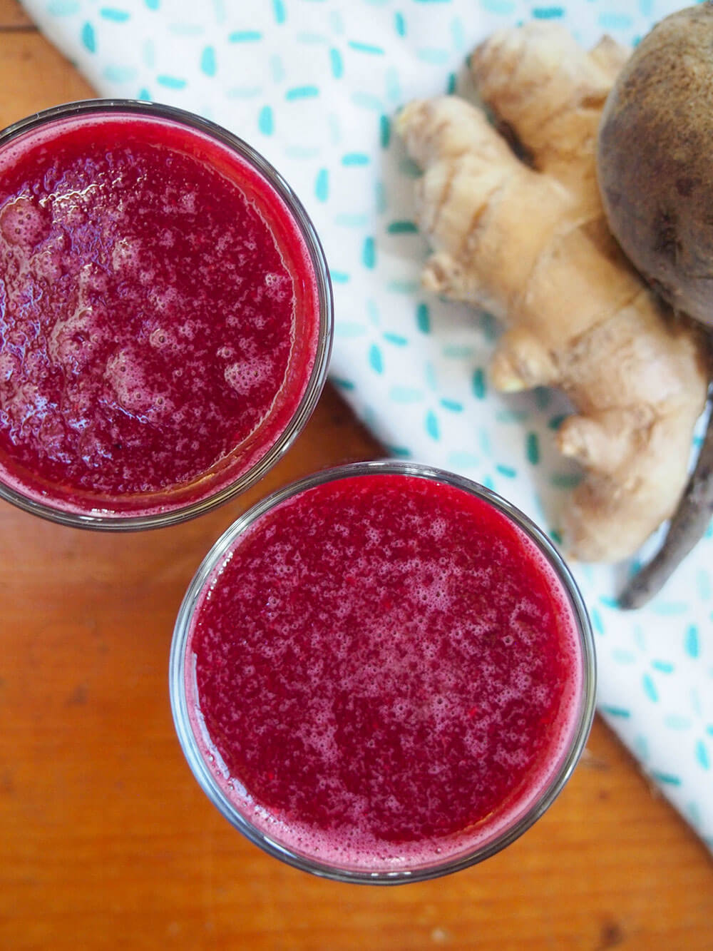glasses of apple beet ginger juice from overhead with beet and ginger piece to side