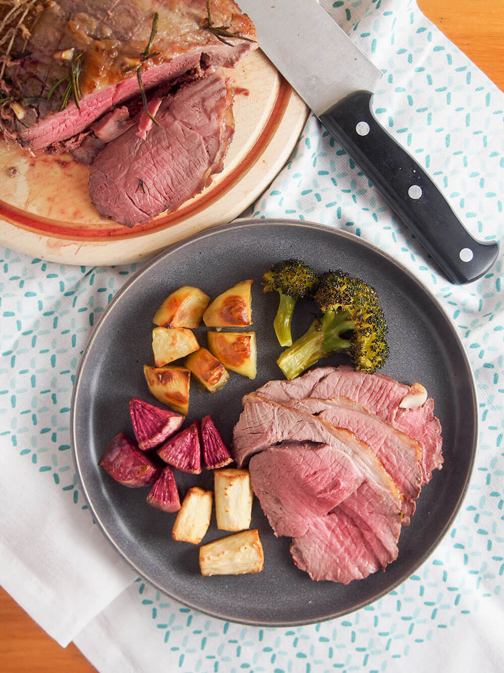 overhead view of plate with slices of lamb and roasted vegetables as side