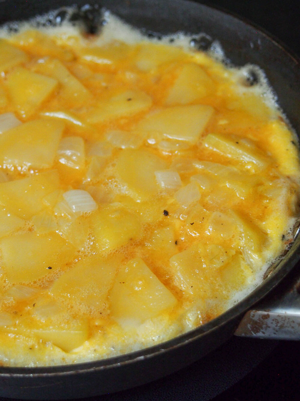 cooking Spanish tortilla, tortilla espanola cooking first side of Spanish tortilla in skillet