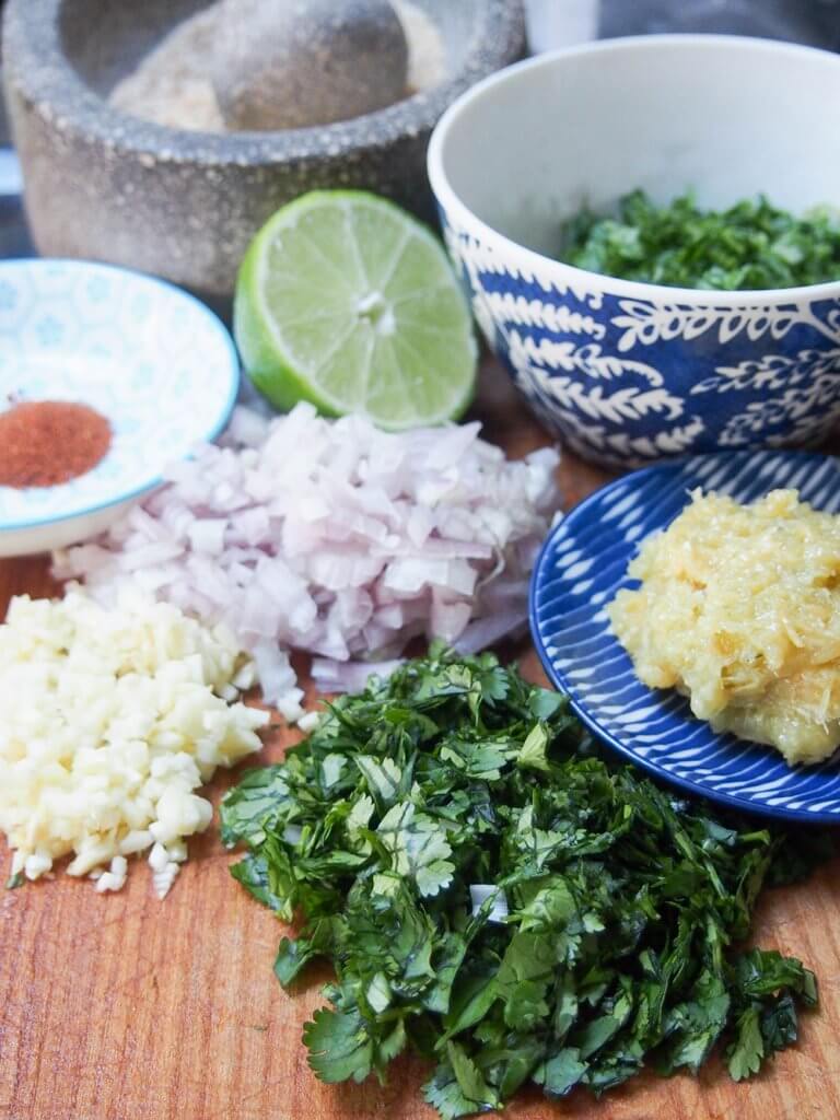 ingredients laid out to make larp - chopped herbs, lime, spices, shallot, garlic and lemongrass