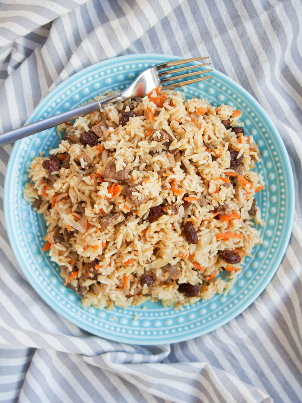 plate of lamb pilaf with fork at top of plate viewed form overhead