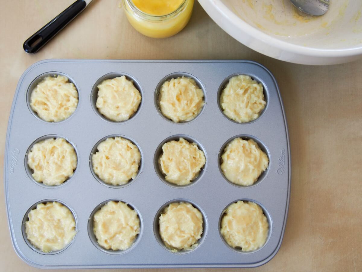 filled mini lemon almond flour muffins ready to bake with jar of lemon curd behind
