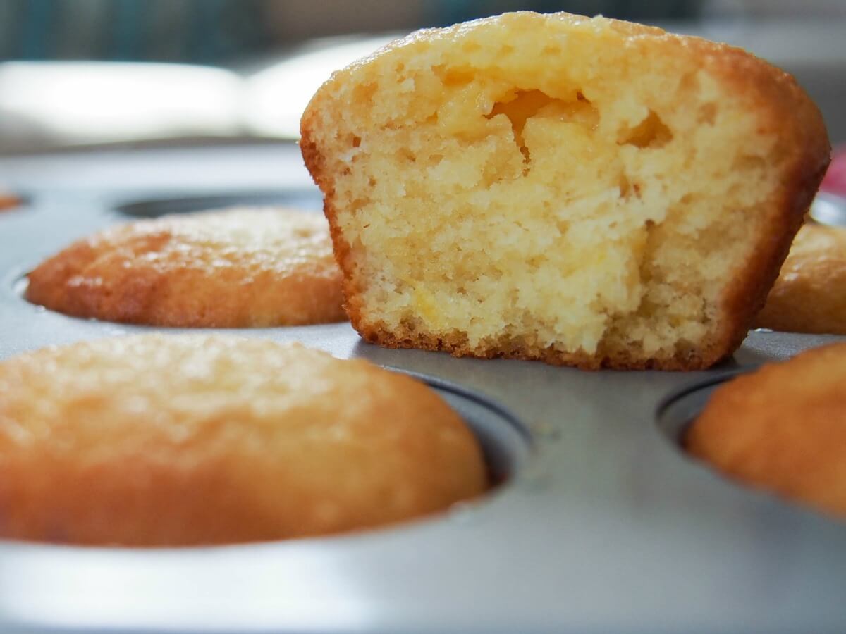 One lemon almond flour muffin sitting on tray holding others