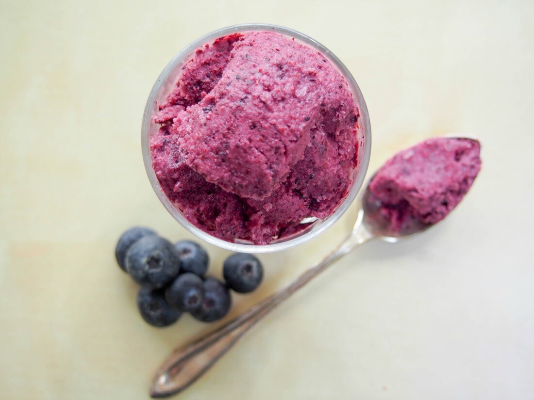 blueberry frozen yogurt in glass with some on food viewed from overhead