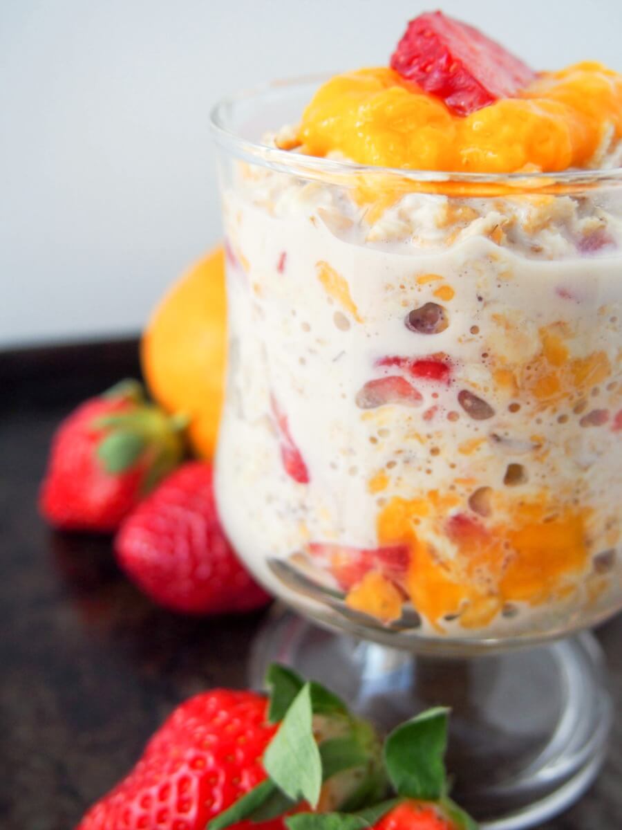 This mango and strawberry overnight oats is the perfect light breakfast for warmer weather. Deliciously smooth, creamy, fresh & fruity. And so easy to make! glass of mango and strawberry overnight oats from side