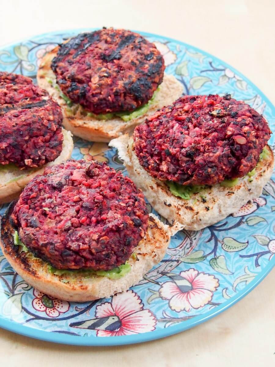 beet and black bean burgers sitting on top of guacamole-toped burger buns, top open