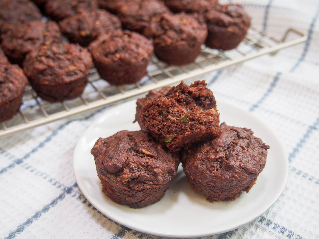Healthy chocolate zucchini muffins (vegan) with some on plate in front