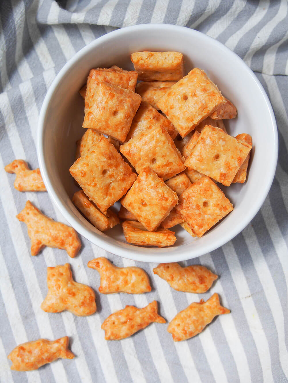 square homemade cheese crackers in bowl and animal-shaped crackers on cloth to side