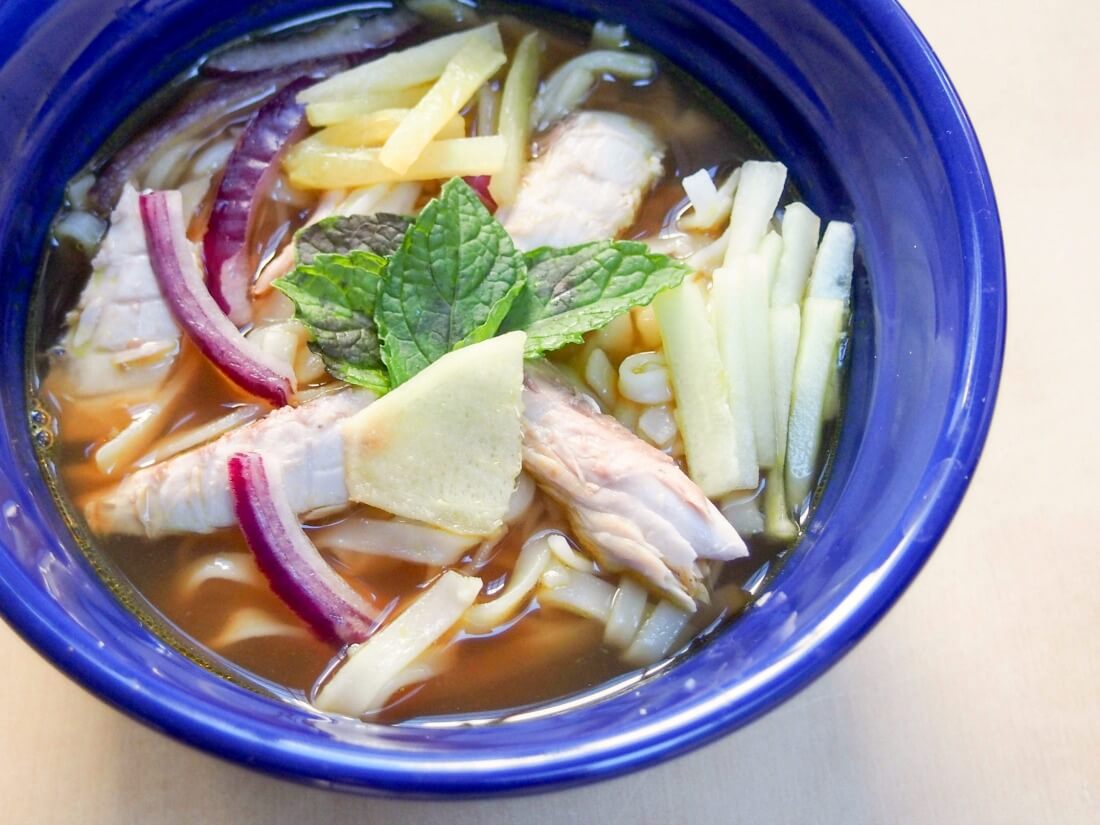 Asam laksa is a deliciously flavorful Asian broth with a fish, tamarind and spicy base, served over rice noodles with cucumber, pineapple and mint garnish.