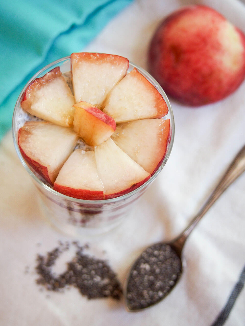 coconut chia pudding with white peach from overhead showing layer of peaches, chia seeds below glass