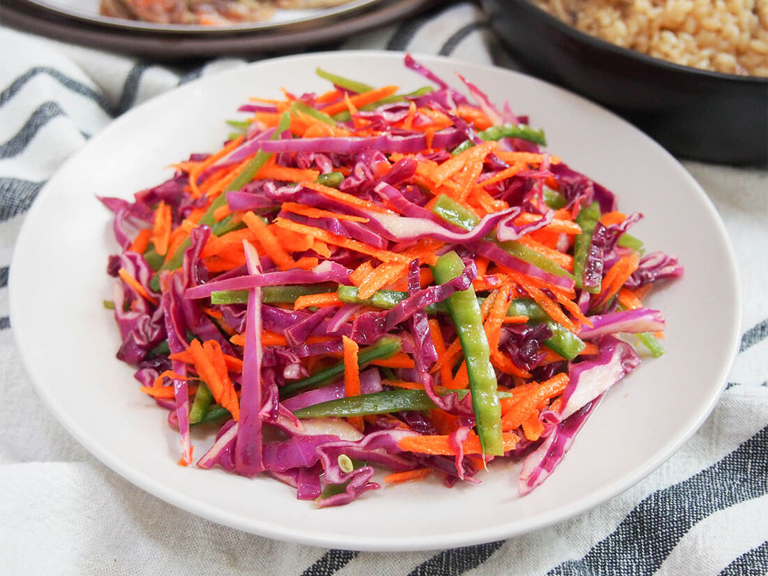 This rainbow slaw has only a few ingredients, but is both bright on your plate and in your mouth. Easy, crunchy and flavorful, it's versatile and great for potlucks and more. rainbow slaw on plate