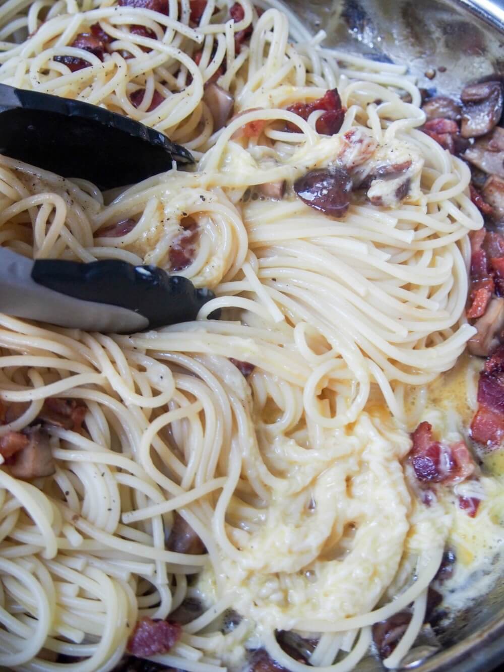 adding egg-cheese mixture to pasta