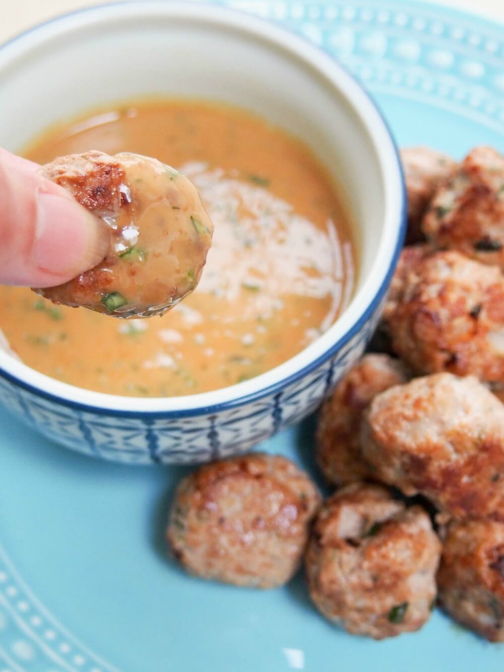 dipping meatball into peanut sauce