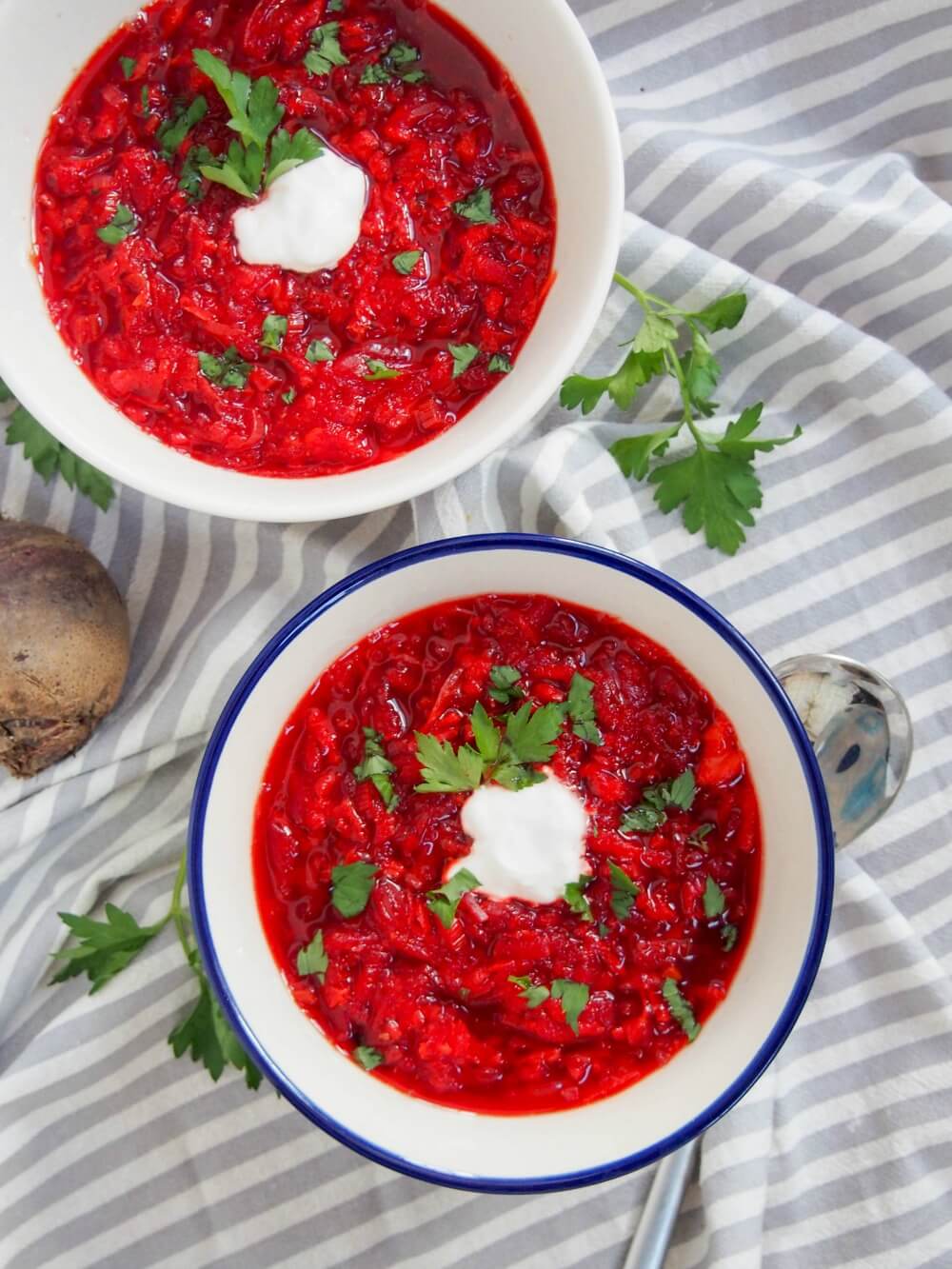 Borscht is one of the iconic dishes from Russia and it's neighbors, but you can know it as a deliciously warming, comforting bowl of soup. It gets much of its color from beets, but there's a whole lot more to this bright bowl. two bowls of borscht - Russian beet soup - from overhead