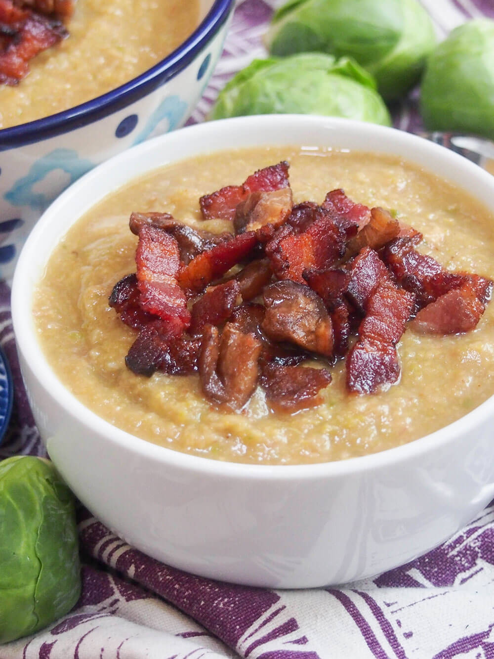 side close view of bowl of Brussel sprout soup with crispy bacon and chestnut on top