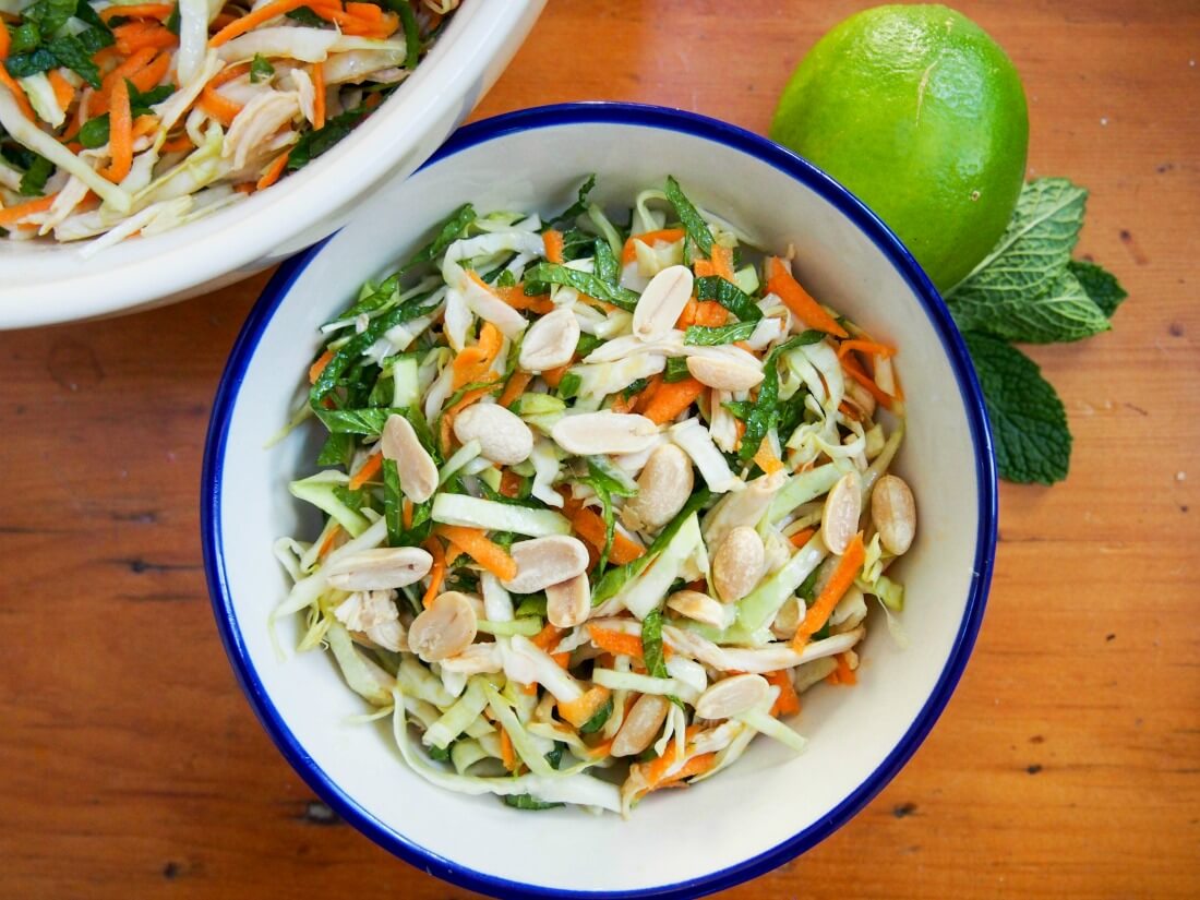 Vietnamese chicken salad is simple but delicious - a great way to enjoy leftover chicken (or turkey) alongside vegetables, mint and a punchy Asian dressing. It's perfect for your lunchbox or to take on a picnic too. bowl of Vietnamese chicken salad from above with lime and mint sprig to side