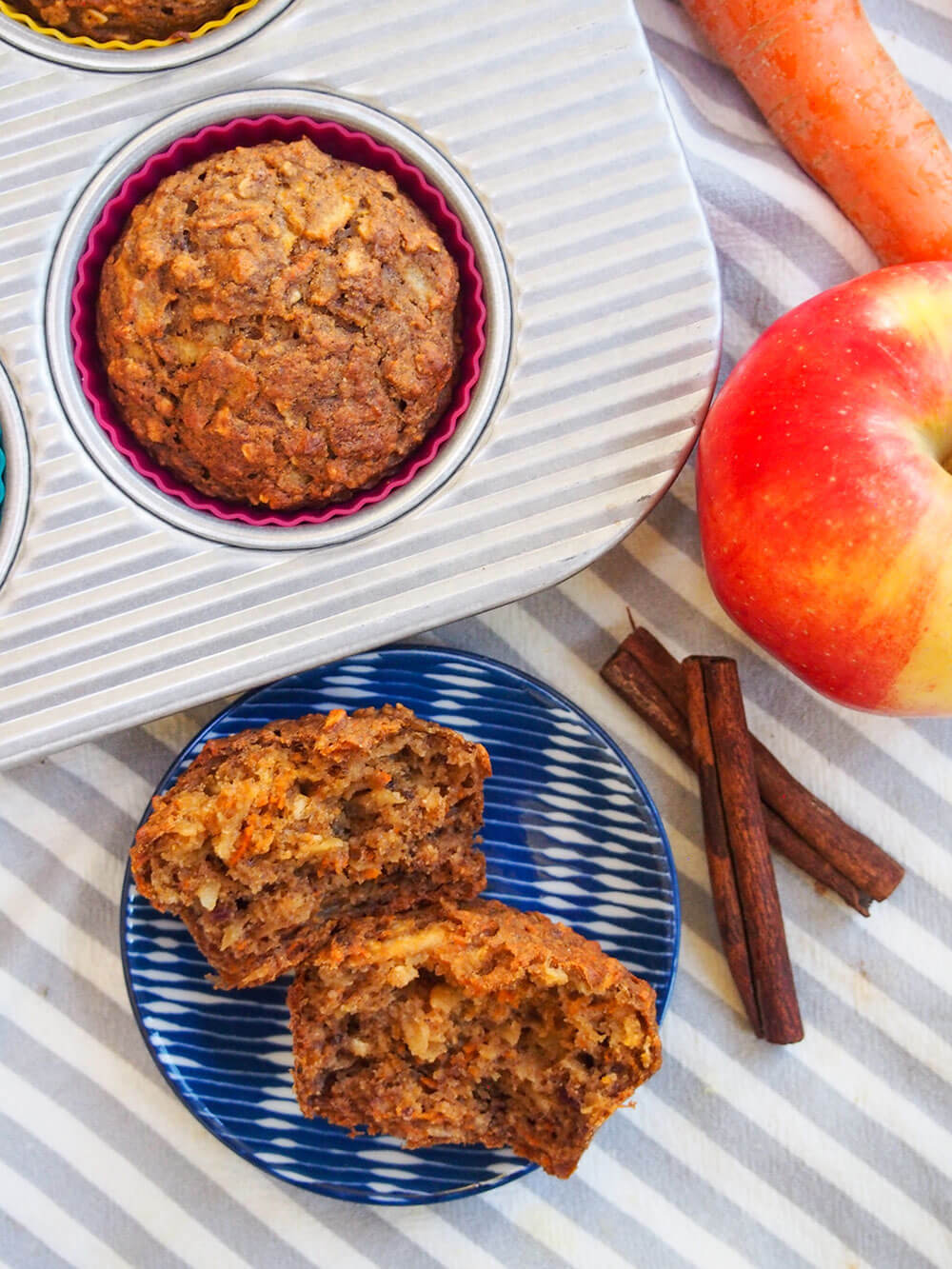 These naturally-sweetened carrot apple muffins have a delicious, gently spiced flavor and moist texture. They're easy to make and perfect for breakfast or a snack. Overhead view of carrot apple muffins with one in tin and one split on plate