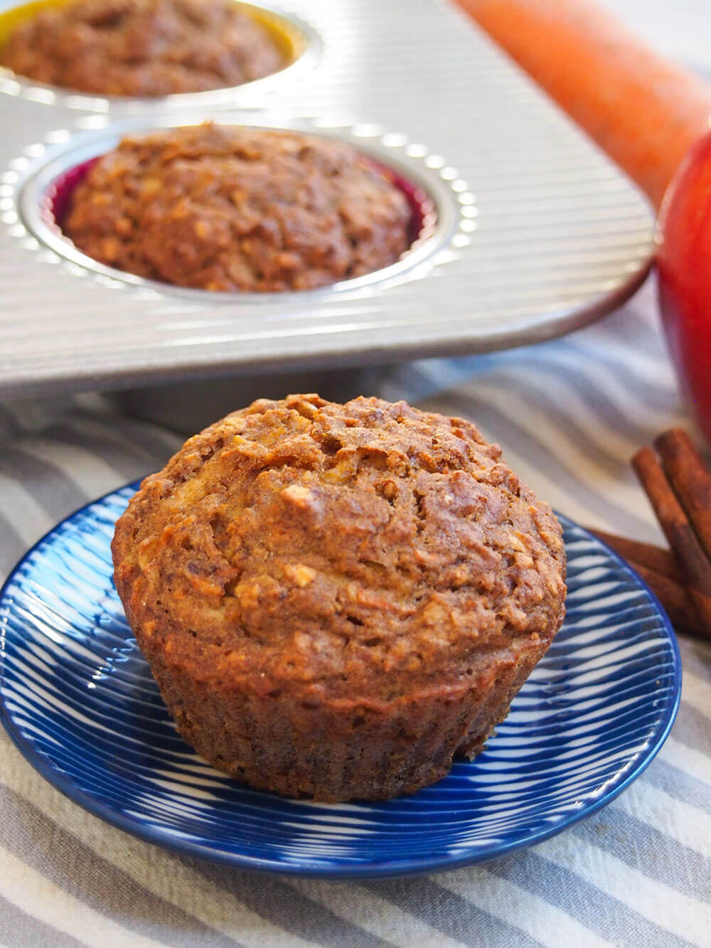 These naturally-sweetened carrot apple muffins have a delicious, gently spiced flavor and moist texture. They're easy to make and perfect for breakfast or a snack. Healthy carrot apple muffins with one on small plate in front of tin