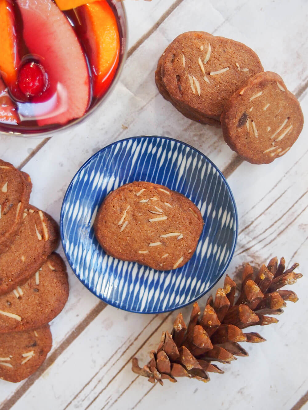 Brunkager - Danish Christmas cookies - viewed form overhead with pine cone to one side and glass of sangria on other