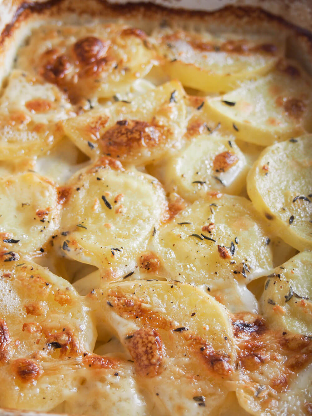 Dauphinoise potatoes are a wonderful combination of creamy potatoes with a touch of garlic and thyme. Rich, meltingly tender and so good. Dauphinoise potatoes in baking dish with browned top