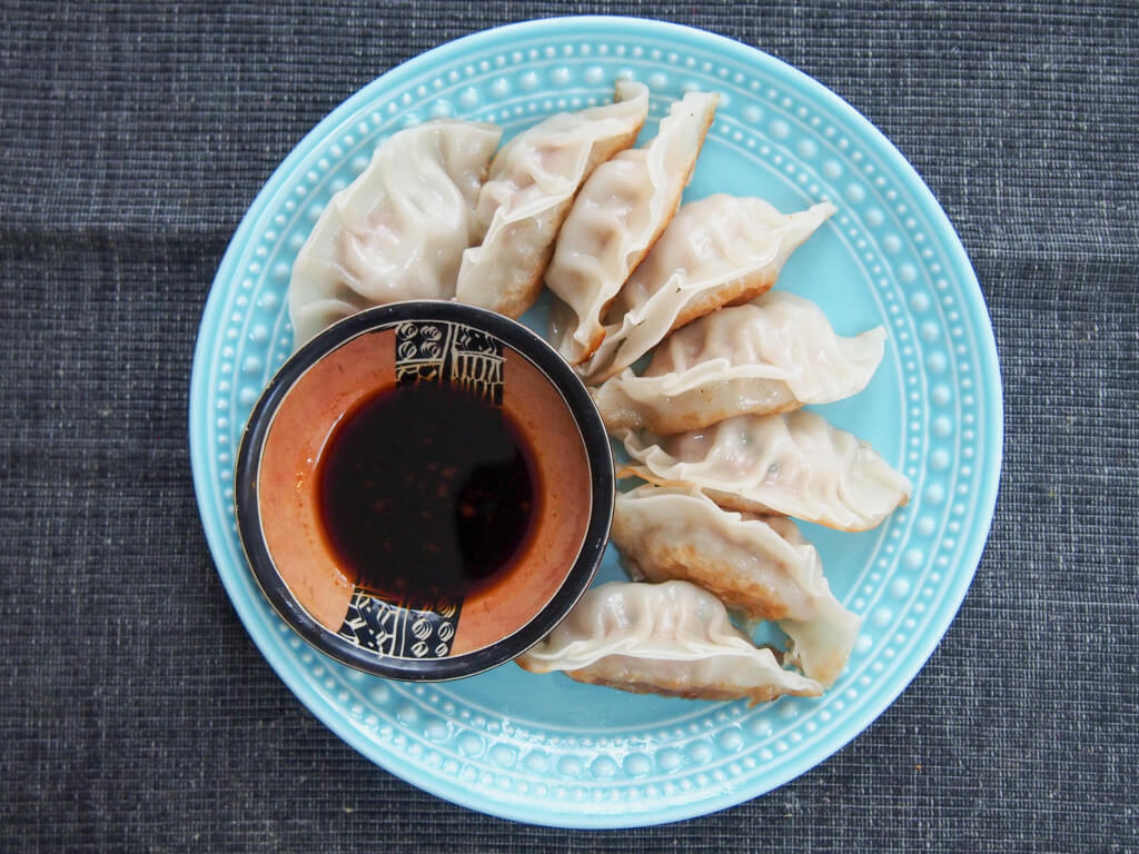 Pork and cabbage dumplings are a traditional dish eaten for Chinese New Year, but these dumplings are so delicious you'll want to have them more often! Chinese pork and cabbage dumplings on plate from overhead