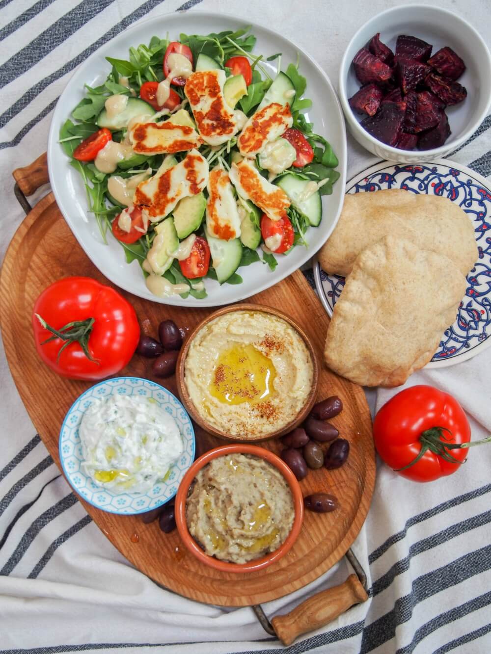 Baba ghanoush (or baba ganoush) is one of many dips/spread that's a staple on mezze plates. This eggplant dip tastes so creamy, with a wonderful smokey flavor, but it's entirely vegan. Easy, versatile and moreishly delicious. baba ghanoush eggplant dip/spread (baba ganoush) along with hummus, halloumi salad and other mezze