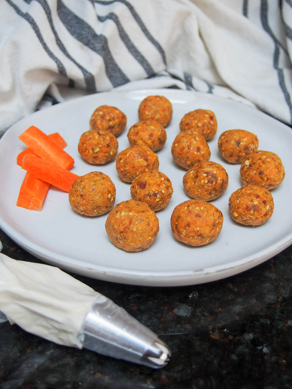 carrot cake energy bites ready to put on topping with piping bag in front of plate