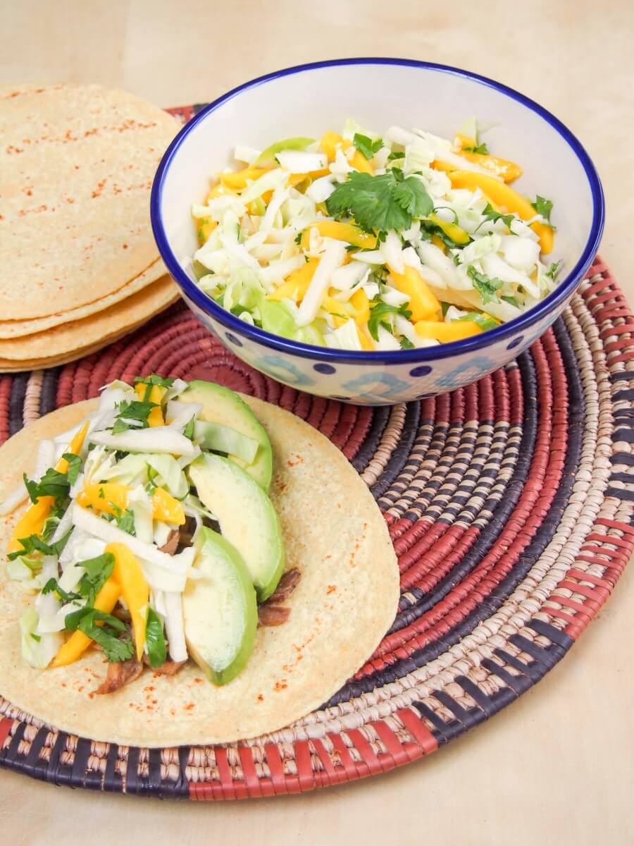 mango jicama slaw served on top of taco with bowl of slaw to side