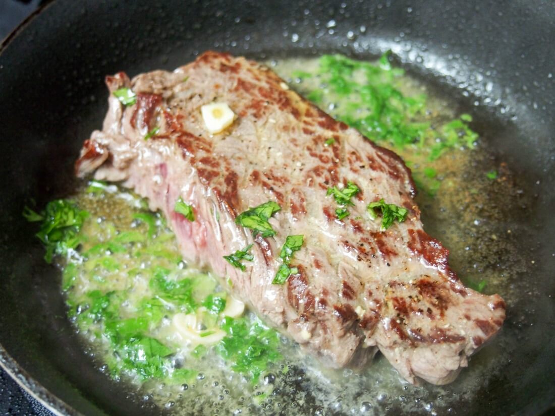 cooking white wine marinated steak in skillet