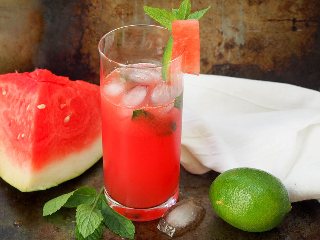 watermelon mojito in glass with lime to side and watermelon on other