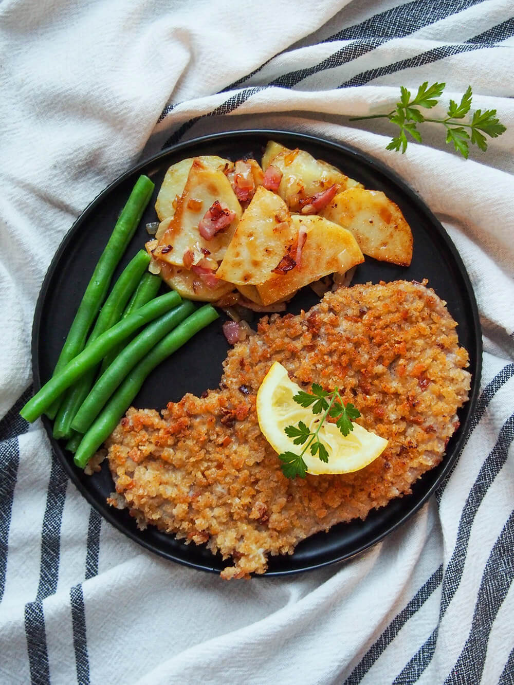 plate with Wiener schnitzel, green beans and potatoes viewed from overhead