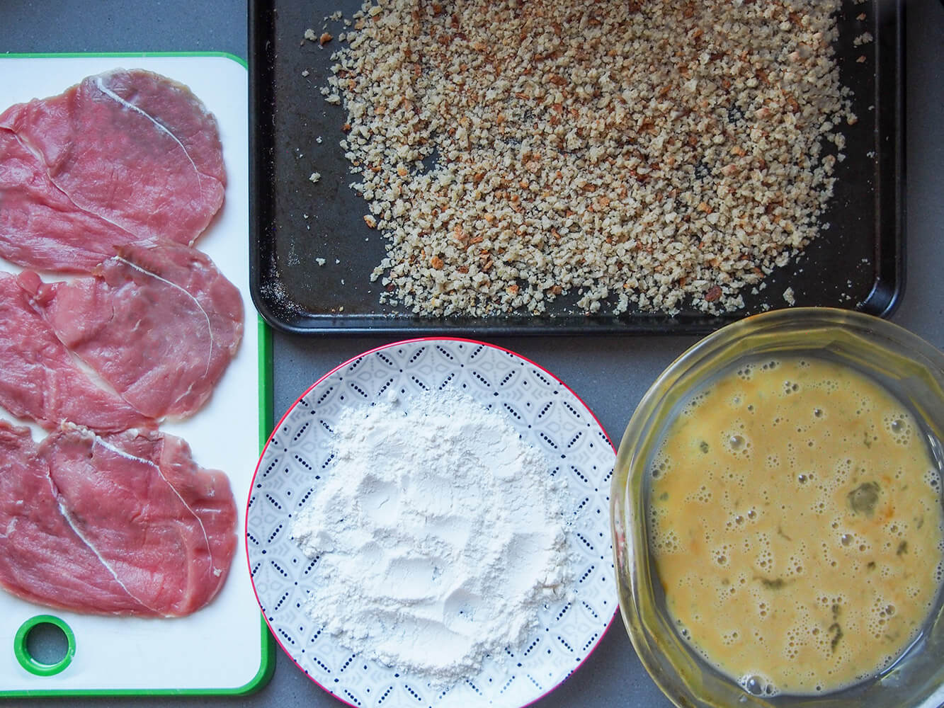 slices of veal, plate with flour, dish with egg and plate of breadcrumbs