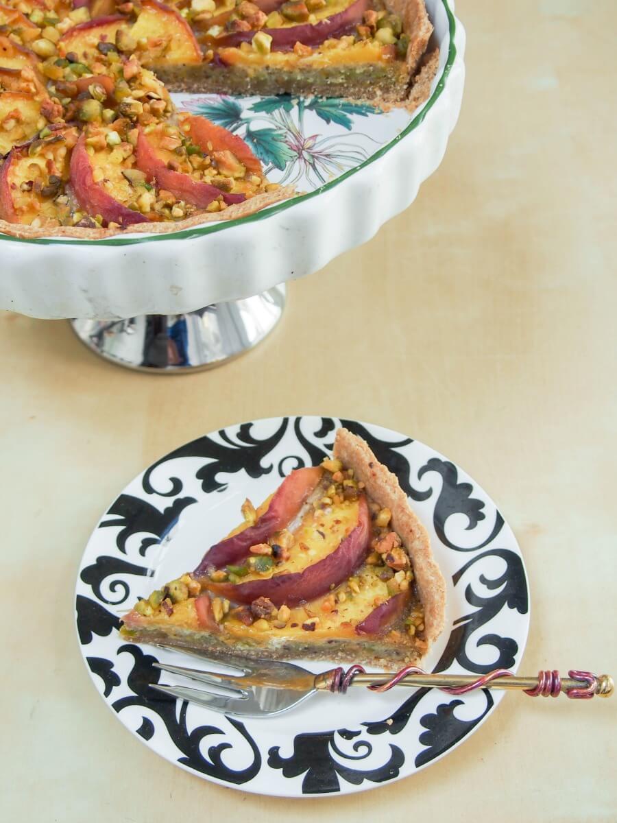 slice of tart on plate with rest of tart behind on stand