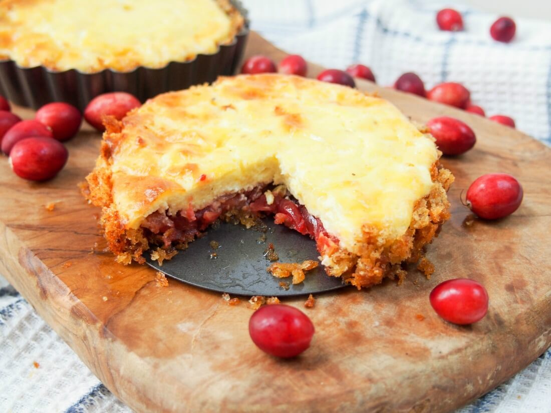 Savory cranberry and cheese tart with slice cut from it and whole tart behind