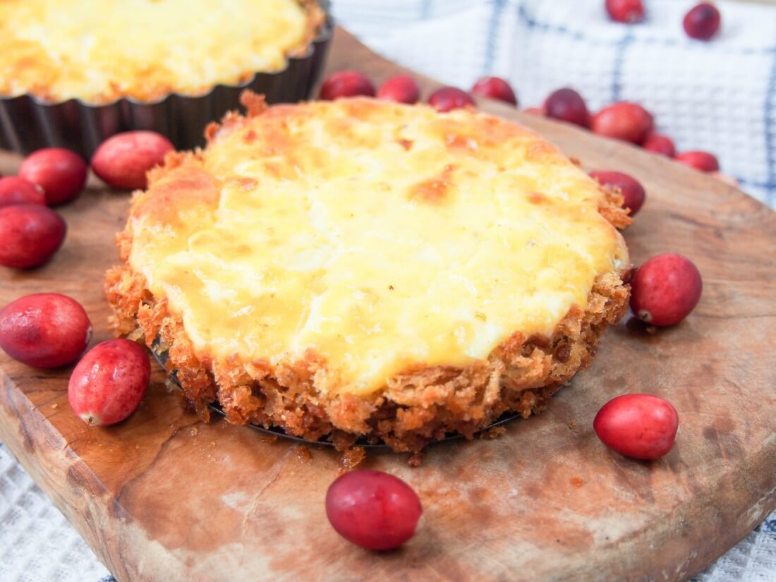 whole tart on wooden board surrounded by cranberries