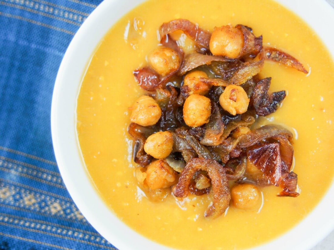 bowl of delicata squash soup with curried chickpeas and onions on top, viewed from overhead