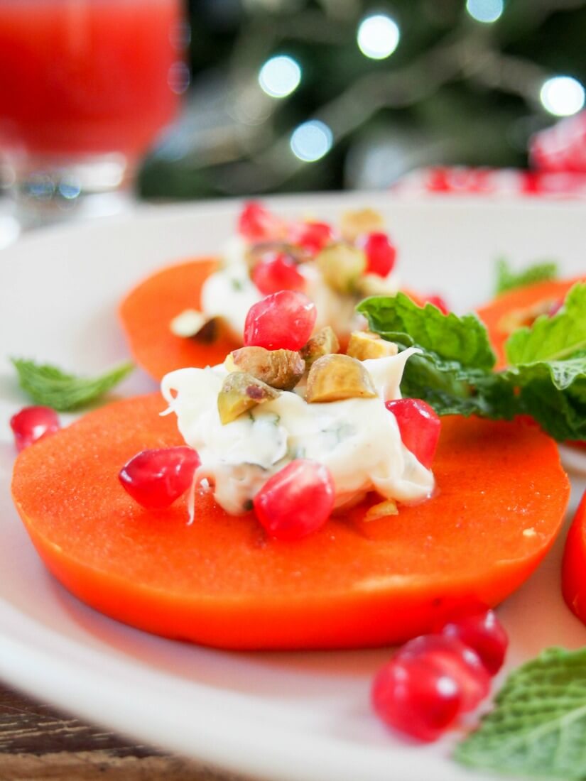 This easy persimmon appetizer is a tasty, colorful addition to any appetizer plate. Incredibly quick to make, a delicious mix of textures. close up of persimmon appetizer with minted mascarpone, decorated with pomegranate and pistachio