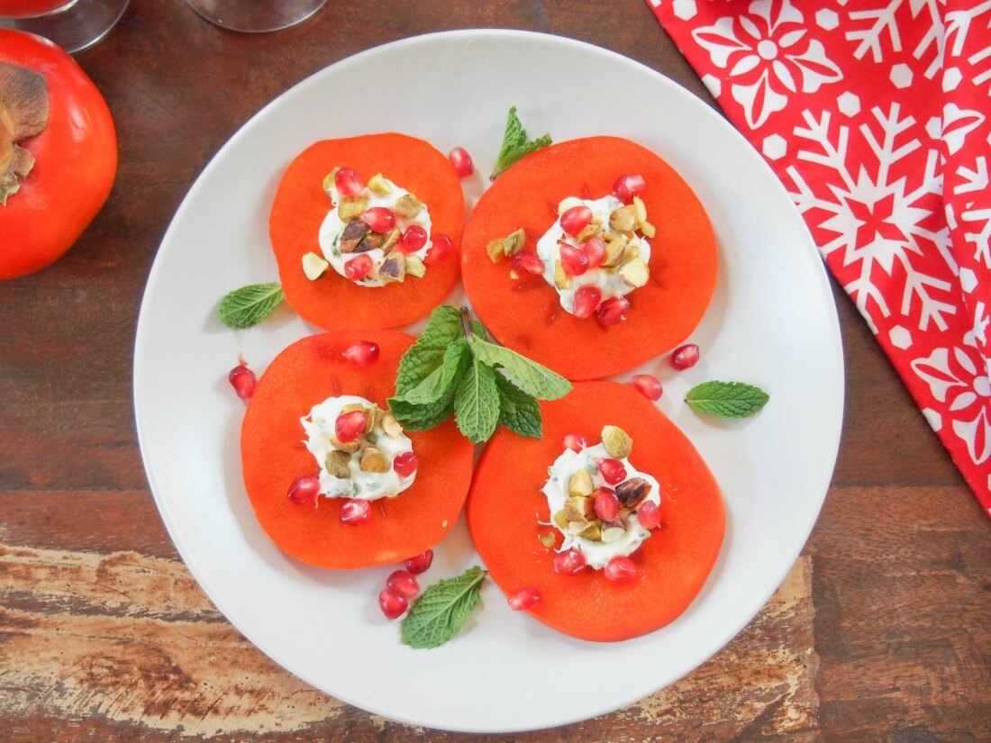 This easy persimmon appetizer is a tasty, colorful addition to any appetizer plate. Incredibly quick to make, a delicious mix of textures. persimmon appetizers on plate from overhead with mint and pomegranate garnishes