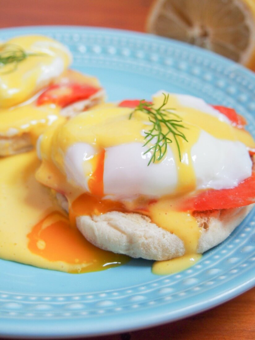 close up of eggs Royale with yolk cut and dripping into Hollandaise sauce
