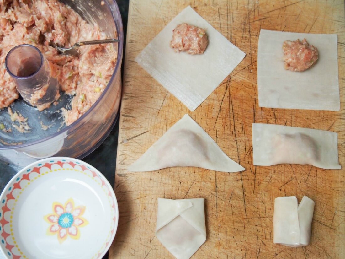 making wontons - filling to side and putting some on wrappers and folding up using two methods